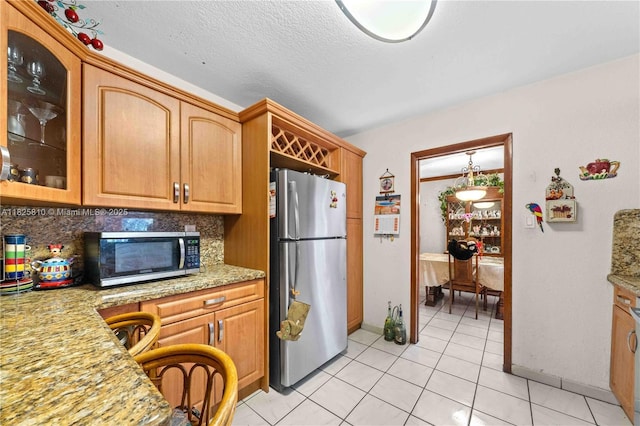 3820 SW 122nd Ave, Miami, FL 33175 - kitchen with stainless steel appliances, light tile patterned floors, backsplash, glass insert cabinets, and a textured ceiling