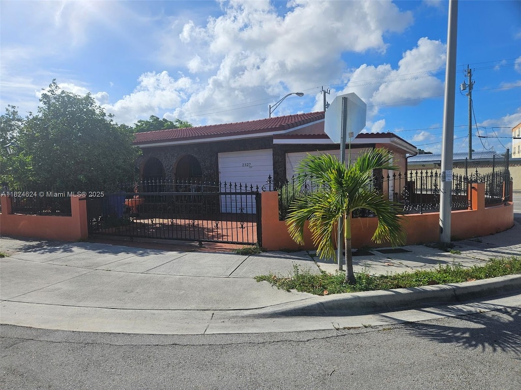 2327 SW 1st St, Miami, FL 33135 - view of front of home with a tiled roof, a fenced front yard, stucco siding, and a garage