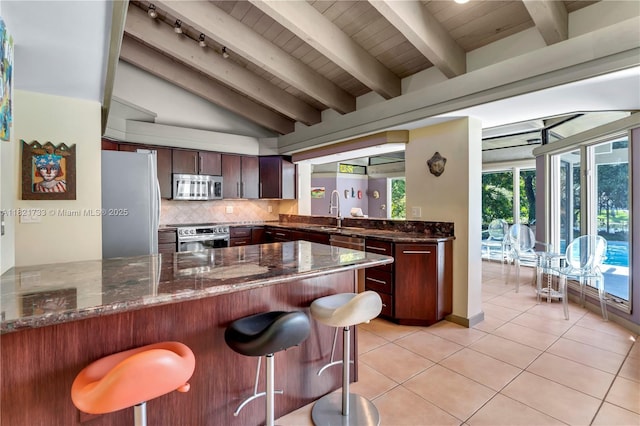 2691 SW 110th Way, Davie, FL 33328 - kitchen with stainless steel appliances, a peninsula, light tile patterned floors, a kitchen breakfast bar, and decorative backsplash