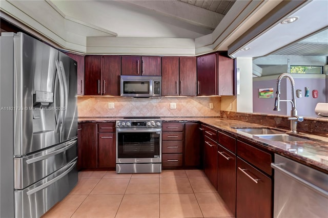 2691 SW 110th Way, Davie, FL 33328 - kitchen featuring appliances with stainless steel finishes, light tile patterned floors, dark stone counters, backsplash, and reddish brown cabinets