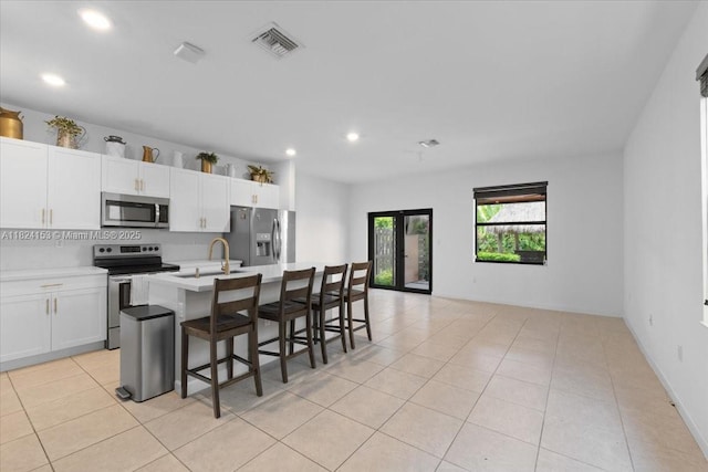 25041 SW 108th Ave, Homestead, FL 33032 - kitchen featuring appliances with stainless steel finishes, recessed lighting, light tile patterned floors, a kitchen island with sink, and white cabinets