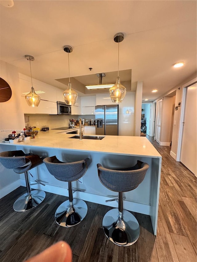 2681 N Flamingo Rd Unit 908S, Sunrise, FL 33323 - kitchen featuring appliances with stainless steel finishes, white cabinets, dark wood-style floors, and a kitchen breakfast bar