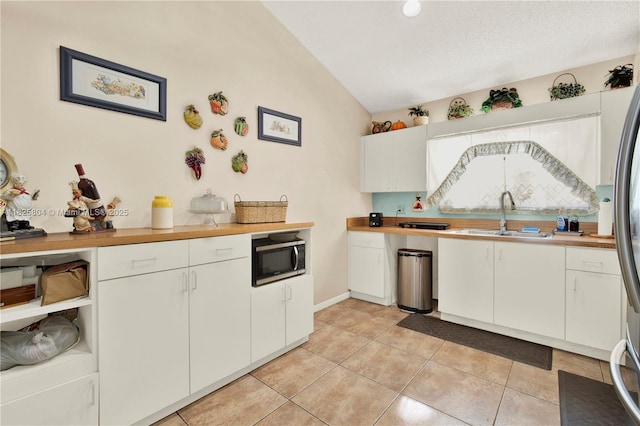 11027 SW 148th Ct, Miami, FL 33196 - kitchen featuring stainless steel microwave, white cabinetry, light tile patterned floors, lofted ceiling, and light countertops