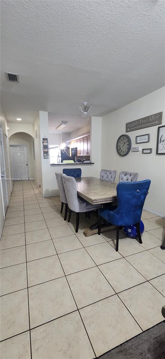 14111 SW 49th St Unit 8, Miramar, FL 33027 - dining space featuring arched walkways, a textured ceiling, and light tile patterned floors
