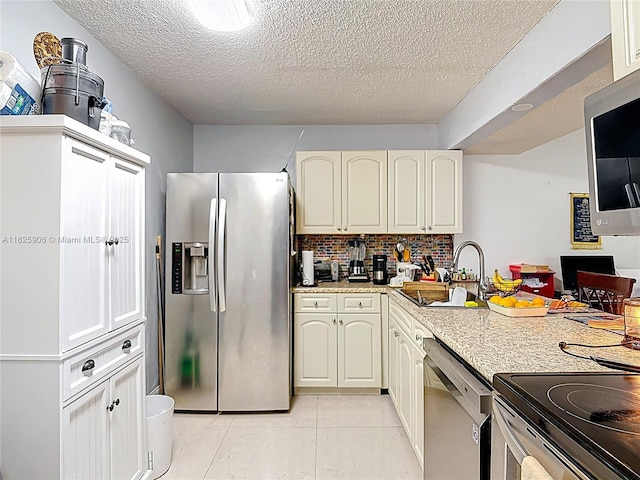 8635 NW 8th St Unit 103, Miami, FL 33126 - kitchen with stainless steel appliances, a textured ceiling, tasteful backsplash, and light tile patterned floors