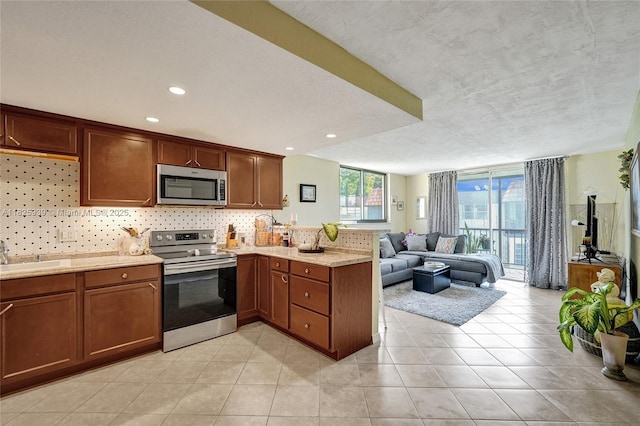 7100 NW 17th St Unit 402, Plantation, FL 33313 - kitchen with stainless steel appliances, a peninsula, backsplash, open floor plan, and light tile patterned floors
