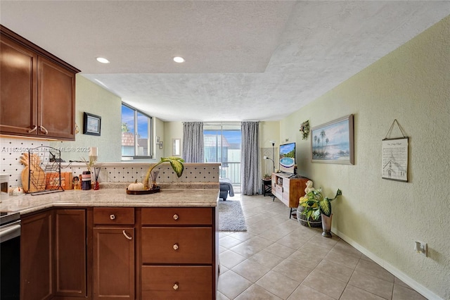 7100 NW 17th St Unit 402, Plantation, FL 33313 - kitchen with a textured ceiling, a textured wall, a peninsula, light tile patterned flooring, and light stone countertops