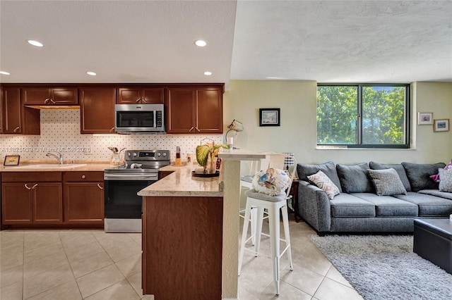 7100 NW 17th St Unit 402, Plantation, FL 33313 - kitchen with appliances with stainless steel finishes, a breakfast bar area, light countertops, backsplash, and recessed lighting