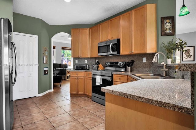 12779 SW 27th St, Miramar, FL 33027 - kitchen with stainless steel appliances, light tile patterned floors, decorative backsplash, arched walkways, and a peninsula