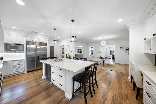 441 Grand Concourse, Miami Shores, FL 33138 - kitchen with built in appliances, a kitchen breakfast bar, white cabinetry, recessed lighting, and light wood-type flooring