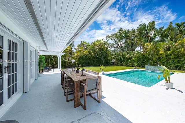 441 Grand Concourse, Miami Shores, FL 33138 - outdoor pool featuring a patio, outdoor dining space, french doors, view of wooded area, and a lawn