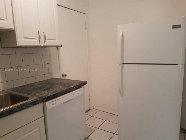 559 NW 44th St, Miami, FL 33127 - kitchen featuring white appliances, decorative backsplash, white cabinetry, dark countertops, and light tile patterned flooring