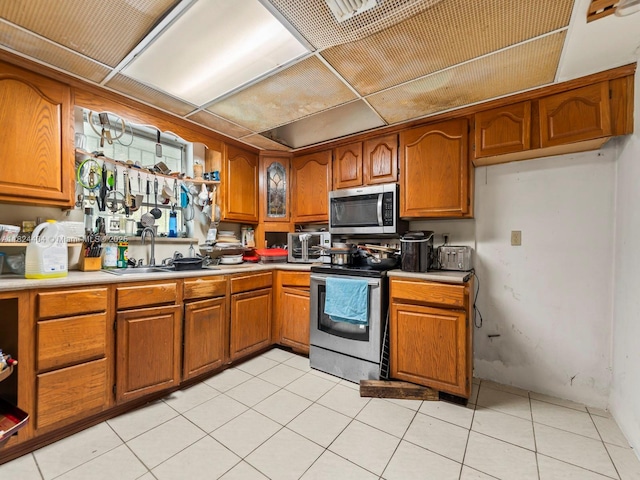 17430 SW 92nd Ct, Palmetto Bay, FL 33157 - kitchen with appliances with stainless steel finishes, brown cabinets, light countertops, and light tile patterned floors