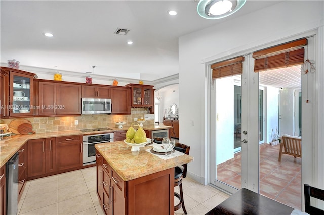 14241 SW 30th St, Miami, FL 33175 - kitchen with stainless steel appliances, decorative backsplash, a breakfast bar area, light tile patterned floors, and recessed lighting