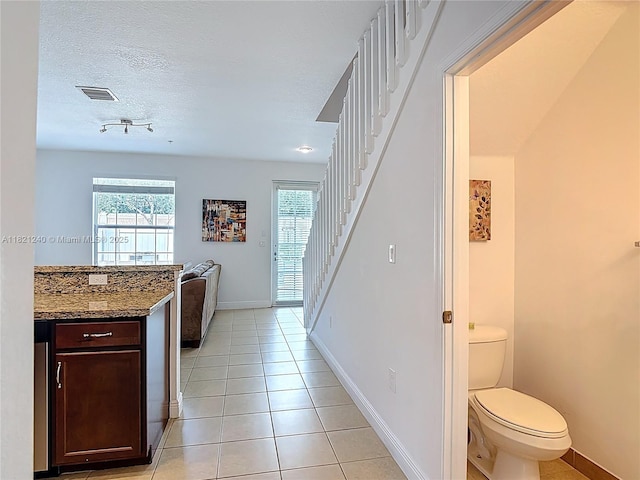 1214 SW 147th Ter, Pembroke Pines, FL 33027 - kitchen with light tile patterned flooring, healthy amount of natural light, dark brown cabinetry, stone countertops, and a textured ceiling