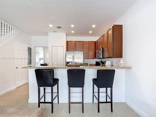 1214 SW 147th Ter, Pembroke Pines, FL 33027 - kitchen featuring stainless steel appliances, a peninsula, a kitchen bar, recessed lighting, and light tile patterned flooring