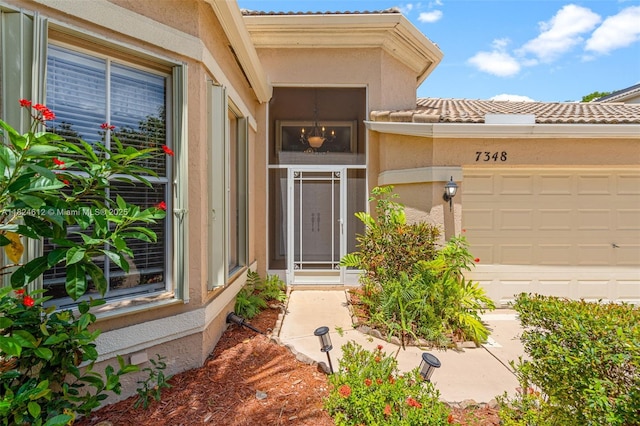 7348 Copperfield Cir, Lake Worth, FL 33467 - view of exterior entry with a tile roof, an attached garage, and stucco siding