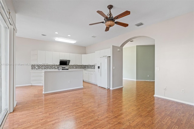 7348 Copperfield Cir, Lake Worth, FL 33467 - kitchen featuring white refrigerator with ice dispenser, ceiling fan, arched walkways, light wood-type flooring, and a center island with sink