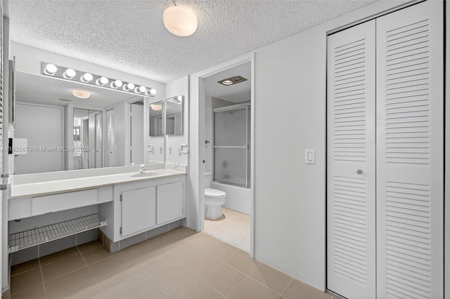 3701 N Country Club Dr Unit 2209, Aventura, FL 33180 - bathroom with a closet, vanity, a textured ceiling, combined bath / shower with glass door, and tile patterned floors