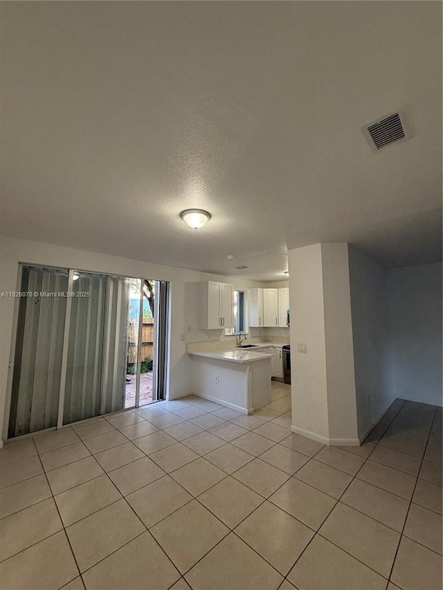 2452 SE 14th Ave Unit 284, Homestead, FL 33035 - kitchen with light tile patterned flooring, a peninsula, light countertops, white cabinetry, and open floor plan
