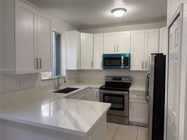 2452 SE 14th Ave Unit 284, Homestead, FL 33035 - kitchen with stainless steel appliances, a peninsula, light stone counters, and white cabinetry