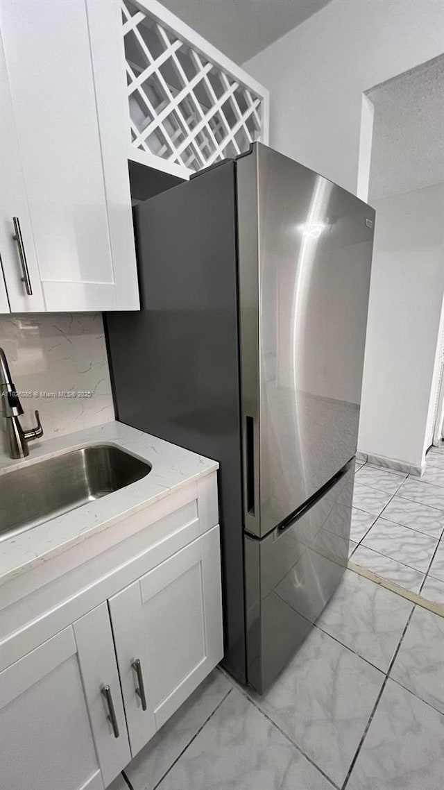 8095 NW 8th St Unit 103, Miami, FL 33126 - kitchen with light marble finish floors, freestanding refrigerator, white cabinets, and tasteful backsplash