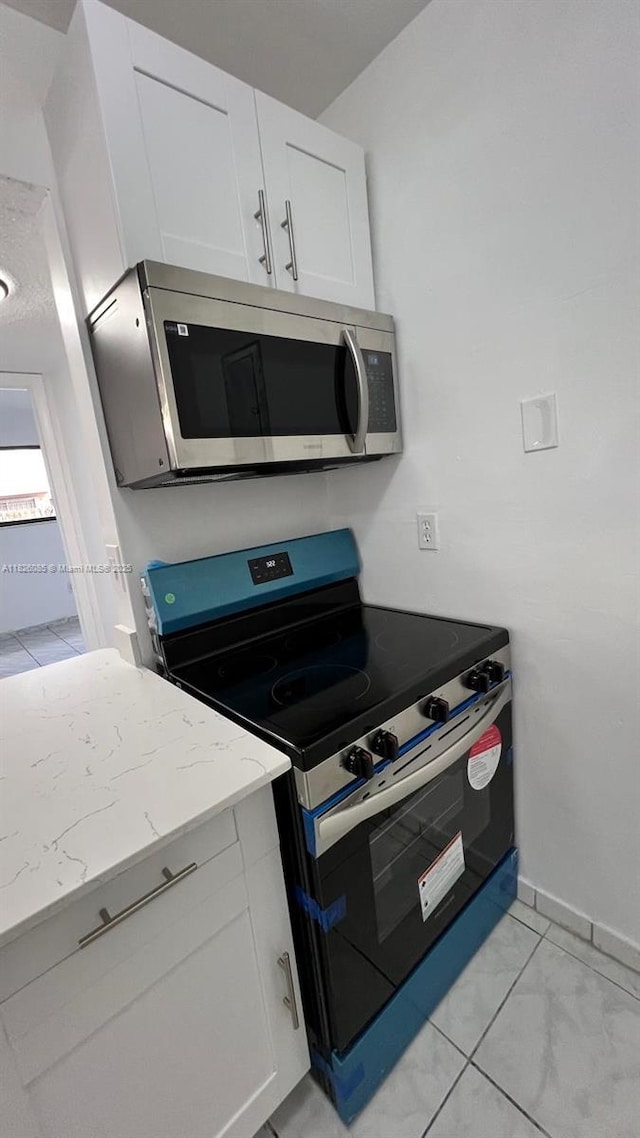 8095 NW 8th St Unit 103, Miami, FL 33126 - kitchen featuring stainless steel appliances, light stone countertops, white cabinets, and light marble finish flooring