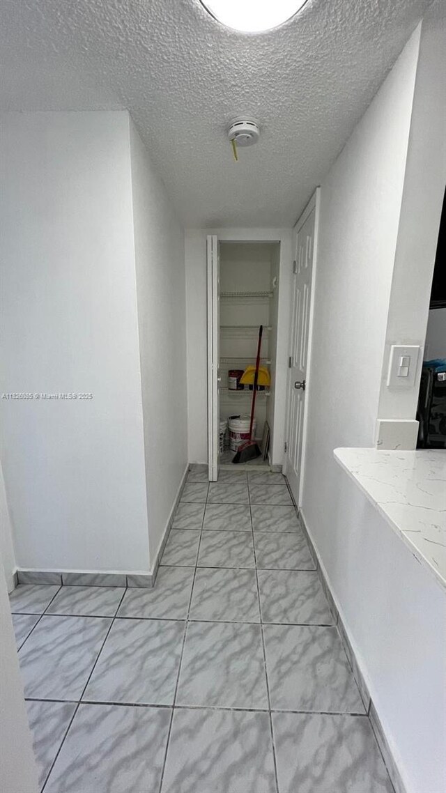 8095 NW 8th St Unit 103, Miami, FL 33126 - hallway featuring light marble finish floors and a textured ceiling