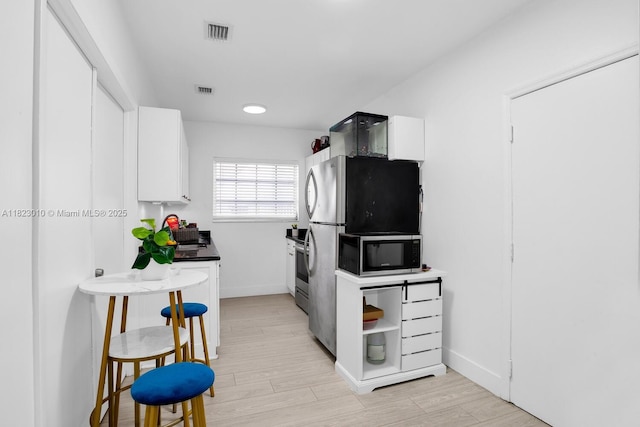 631 Euclid Ave Unit 8, Miami Beach, FL 33139 - kitchen with stainless steel microwave, white cabinets, and light wood-style flooring