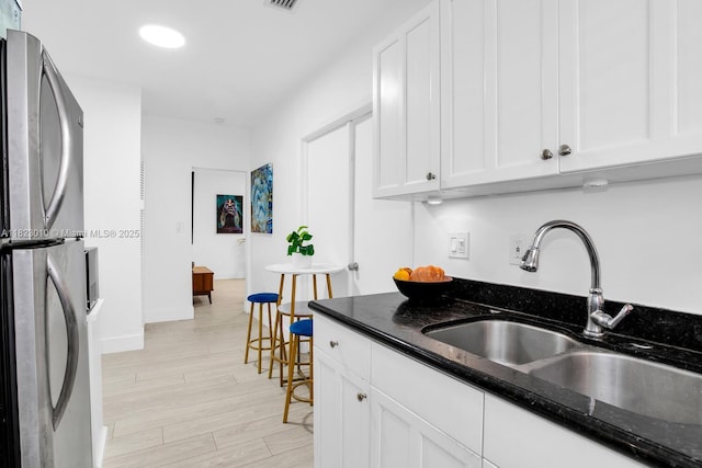 631 Euclid Ave Unit 8, Miami Beach, FL 33139 - kitchen with freestanding refrigerator, white cabinetry, dark stone countertops, and light wood-type flooring