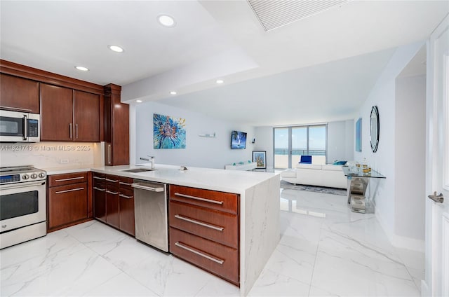 5555 Collins Ave Unit 7N, Miami Beach, FL 33140 - kitchen featuring stainless steel appliances, recessed lighting, a peninsula, light marble finish flooring, and light countertops
