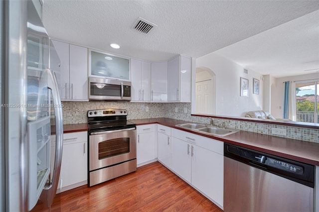 6440 NW 114th Ave Unit 434, Doral, FL 33178 - kitchen featuring appliances with stainless steel finishes, a textured ceiling, white cabinets, dark countertops, and wood finished floors