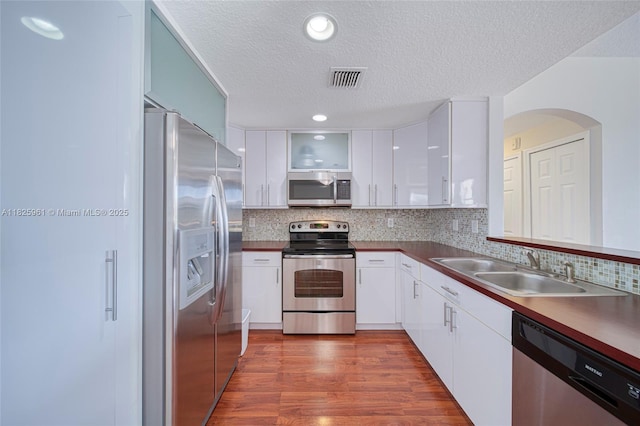 6440 NW 114th Ave Unit 434, Doral, FL 33178 - kitchen with appliances with stainless steel finishes, a textured ceiling, white cabinetry, dark wood-style floors, and decorative backsplash