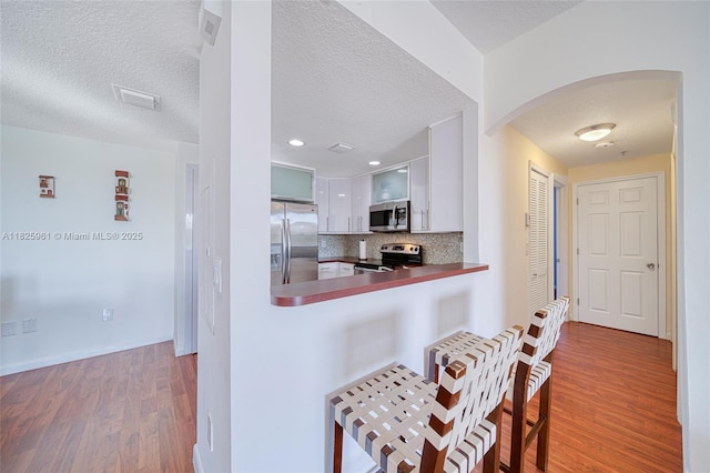 6440 NW 114th Ave Unit 434, Doral, FL 33178 - kitchen with stainless steel appliances, wood finished floors, a kitchen bar, arched walkways, and tasteful backsplash
