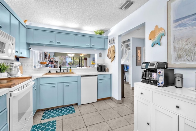 4552 Carambola Cir S Unit 27247, Coconut Creek, FL 33066 - kitchen with white appliances, blue cabinets, light countertops, decorative backsplash, and a textured ceiling
