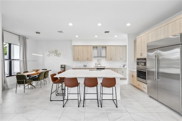 20273 Bandon Dunes Rd, Boca Raton, FL 33434 - kitchen with appliances with stainless steel finishes, light brown cabinetry, wall chimney exhaust hood, modern cabinets, and light countertops