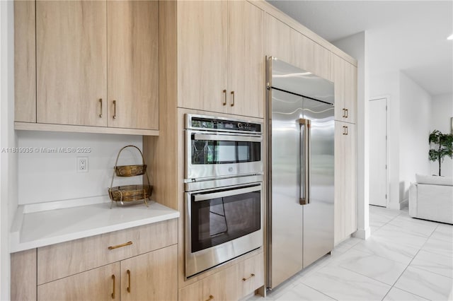 20273 Bandon Dunes Rd, Boca Raton, FL 33434 - kitchen with appliances with stainless steel finishes, light brown cabinets, light countertops, light marble finish floors, and modern cabinets