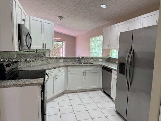 7964 La Rose Ct, Lake Worth, FL 33467 - kitchen with appliances with stainless steel finishes, a textured ceiling, white cabinetry, lofted ceiling, and light stone countertops
