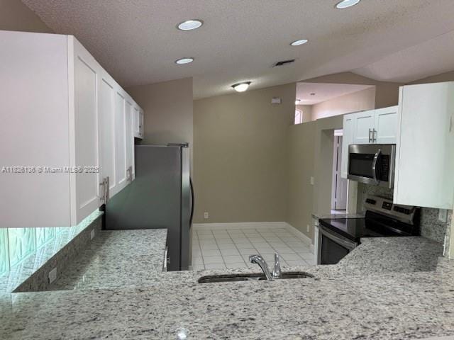 7964 La Rose Ct, Lake Worth, FL 33467 - kitchen with appliances with stainless steel finishes, light stone counters, decorative backsplash, white cabinetry, and vaulted ceiling