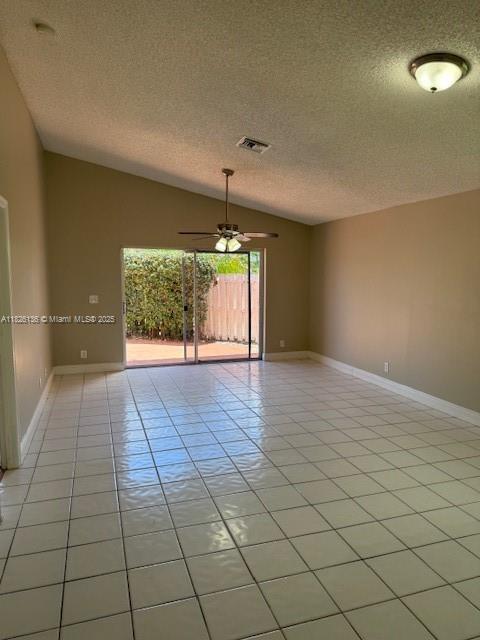 7964 La Rose Ct, Lake Worth, FL 33467 - spare room featuring a textured ceiling, light tile patterned flooring, a ceiling fan, and vaulted ceiling