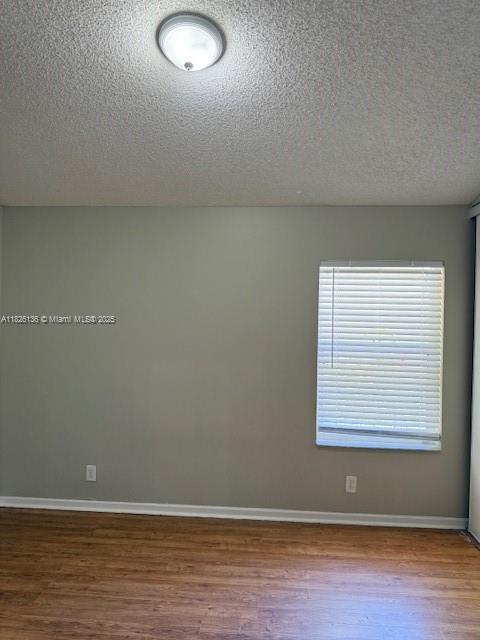 7964 La Rose Ct, Lake Worth, FL 33467 - unfurnished room with a textured ceiling and wood finished floors