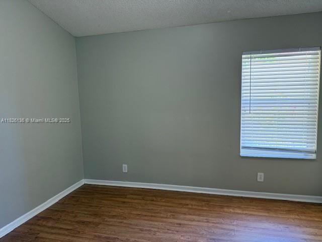 7964 La Rose Ct, Lake Worth, FL 33467 - empty room featuring dark wood-type flooring and a textured ceiling