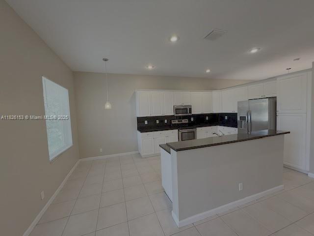 4390 NW 41st Pl, Coconut Creek, FL 33073 - kitchen featuring stainless steel appliances, dark countertops, decorative backsplash, white cabinets, and light tile patterned floors