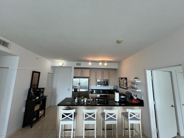 79 SW 12th St Unit 1603-S, Miami, FL 33130 - kitchen featuring appliances with stainless steel finishes, a peninsula, a breakfast bar, dark countertops, and a textured ceiling