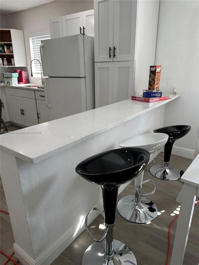 1408 N 23rd St, Fort Pierce, FL 34950 - kitchen with freestanding refrigerator, wood finished floors, light stone counters, and a breakfast bar