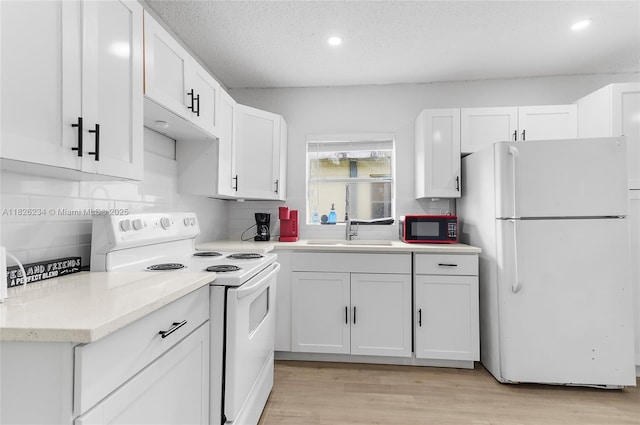 1408 N 23rd St, Fort Pierce, FL 34950 - kitchen featuring white appliances, white cabinets, backsplash, light wood-style flooring, and recessed lighting