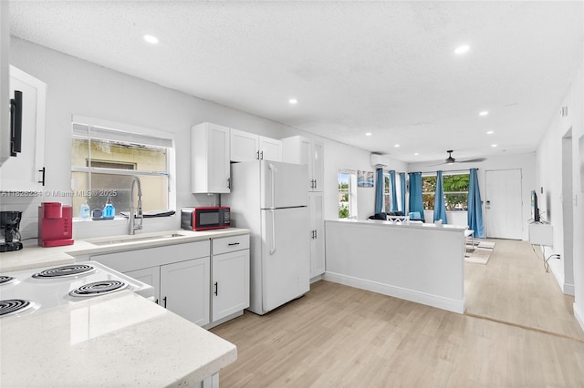 1408 N 23rd St, Fort Pierce, FL 34950 - kitchen featuring white appliances, light wood finished floors, light countertops, recessed lighting, and white cabinetry