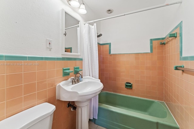 919 NE 4th St, Hallandale Beach, FL 33009 - bathroom with tile walls, shower / bath combo with shower curtain, and a wainscoted wall