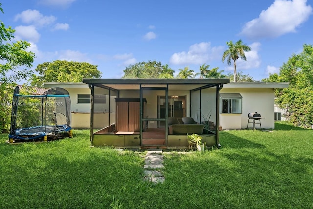 919 NE 4th St, Hallandale Beach, FL 33009 - rear view of property with a trampoline, a sunroom, stucco siding, and a yard