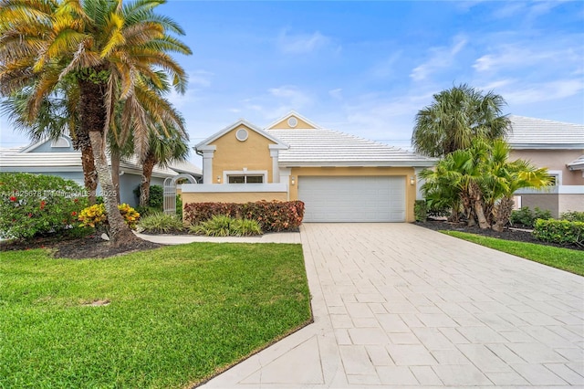 9047 Baybury Ln, West Palm Beach, FL 33411 - view of front facade featuring a garage, a front lawn, decorative driveway, and stucco siding